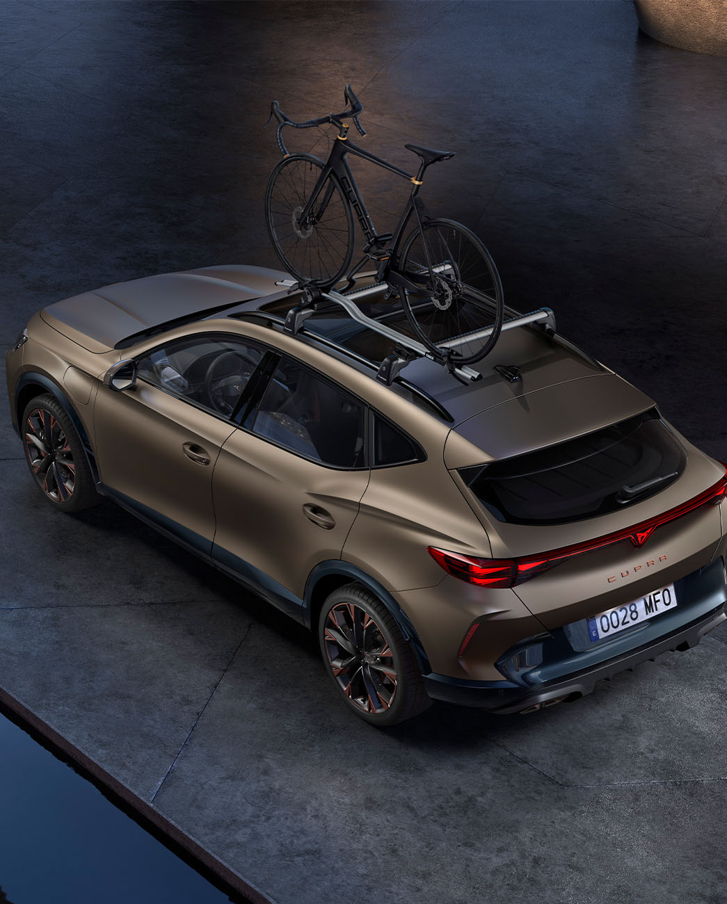 Bird’s eye view of new century bronze matt CUPRA Formentor 2024 with car bike rack accessory, car parked on concrete at dusk.