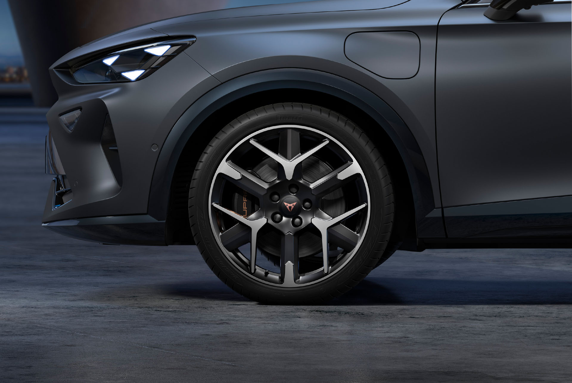 Front side view of left forged CUPRA silver and black car wheels, tyres and signature headlights.